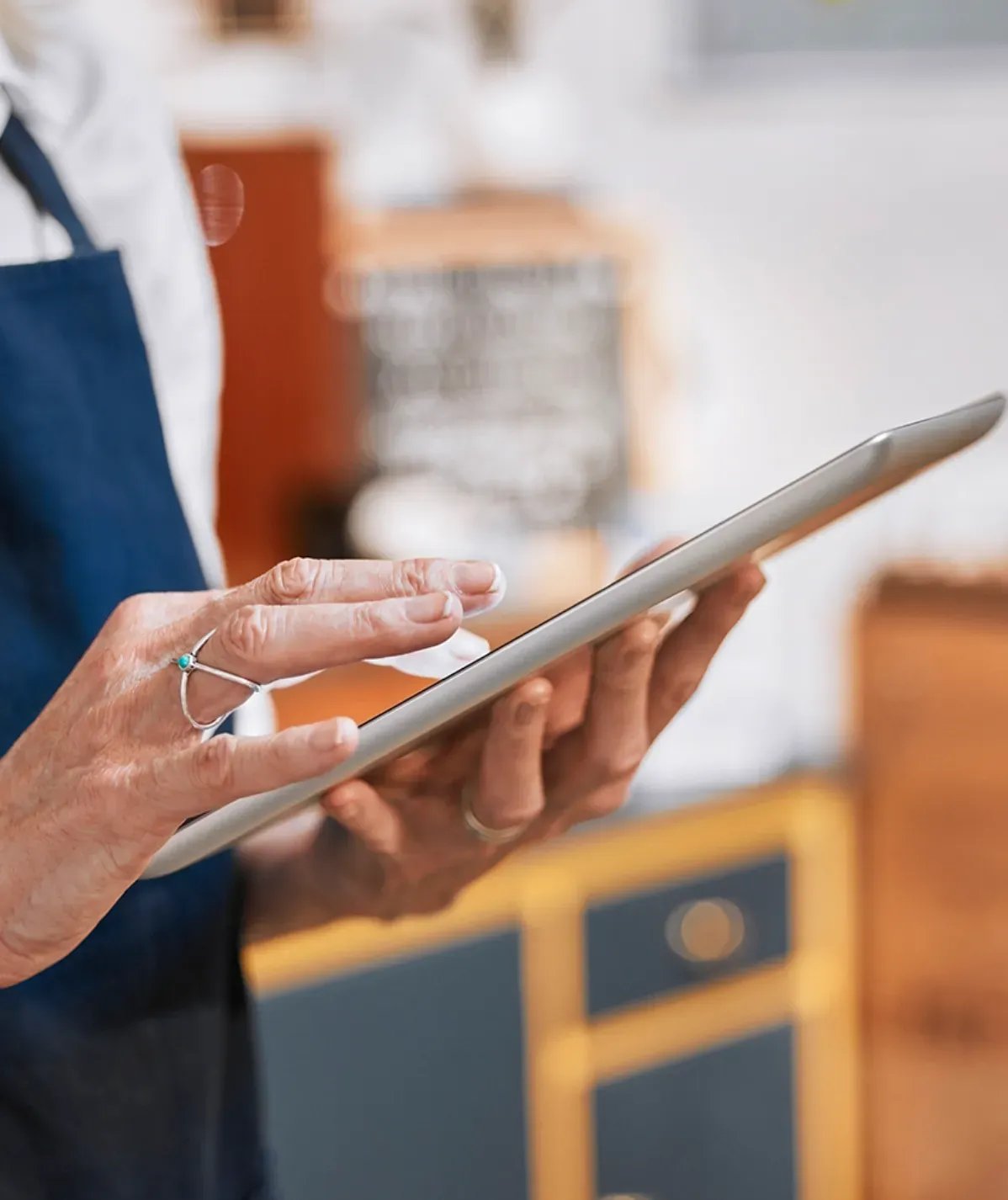 A restaurant worker in an apron reviewing information on a tablet