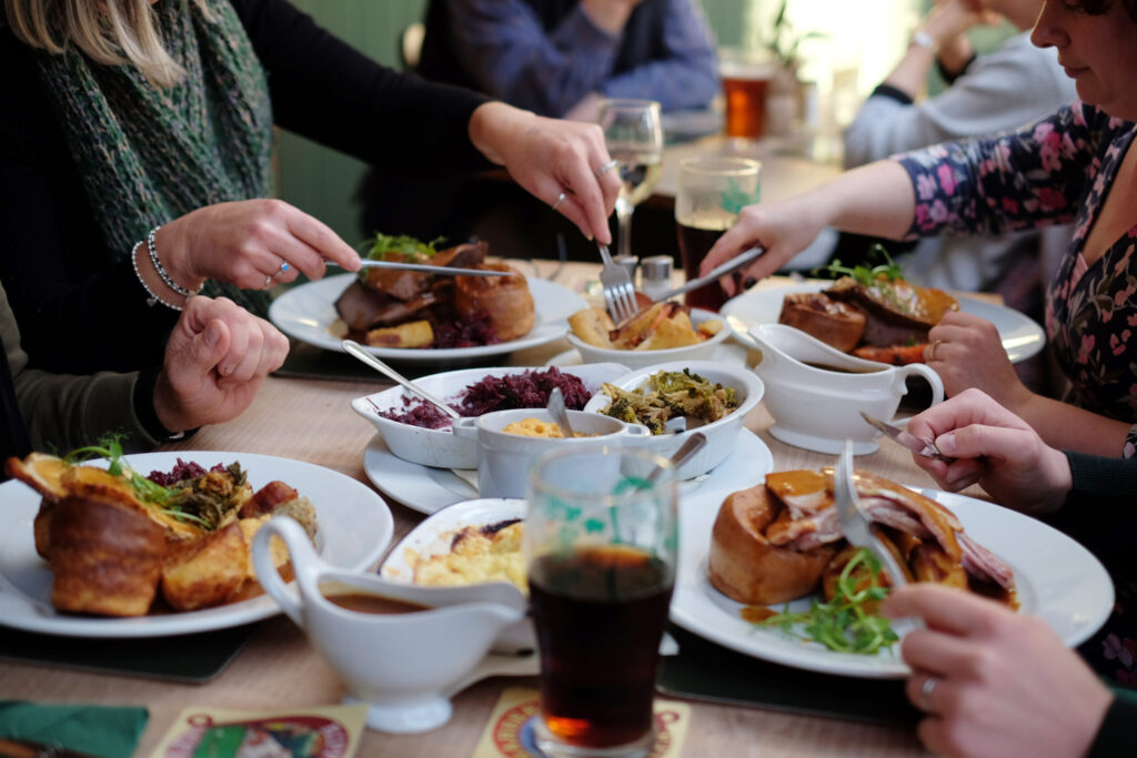 Friends sharing Sunday roasts with Yorkshire puddings, sides and gravy